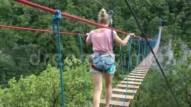 一个穿着安全装备的女孩走在<strong>吊绳</strong>桥上